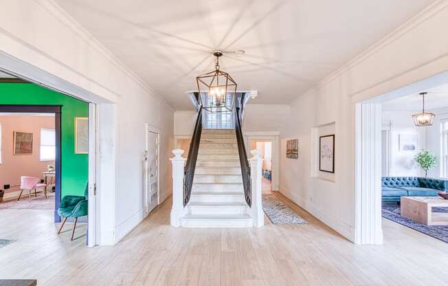 a living room with a staircase and a green wall and a ceiling fan