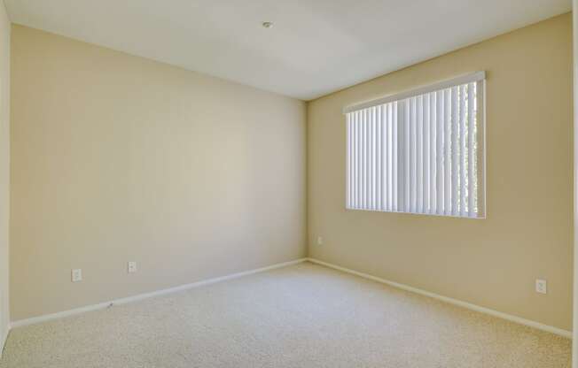 a bedroom with a large window and beige walls