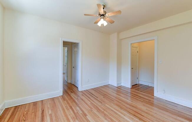 vacant bedroom with hardwood flooring and ceiling fan at the klingle apartments in washignton dc