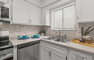 A kitchen with white cabinets and a tiled backsplash.