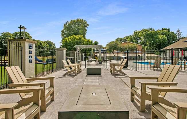 A sunny day at the park with wooden benches and a pool.