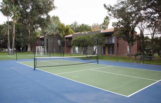 a tennis court with apartments in the background