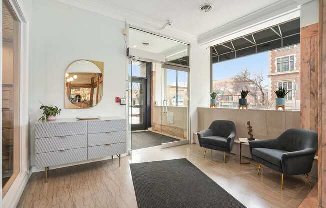a lobby with two chairs and a credenza with a mirror on the wall