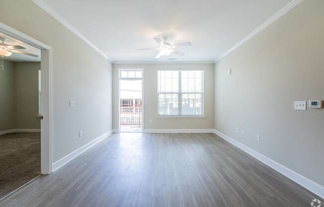 an empty living room with a ceiling fan and a window