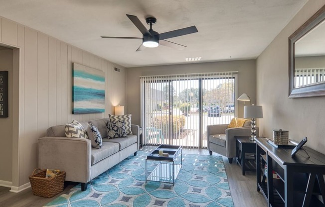 a living room with a couch and a desk and a ceiling fan  at Bayville Apartments, Virginia Beach, VA, 23455