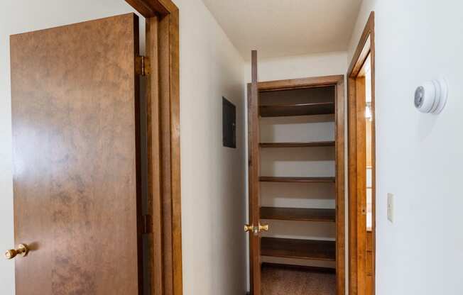 a wooden door opens to a hallway with a staircase and a door to a bathroom. Fargo, ND Hawn Apartments