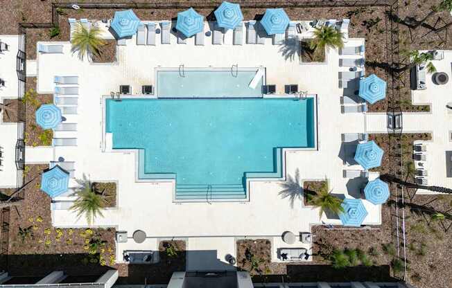 An aerial view of a swimming pool surrounded by lounge chairs and umbrellas.
