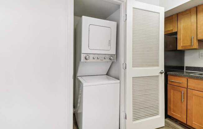 a white washer and dryer in a kitchen with wood cabinets