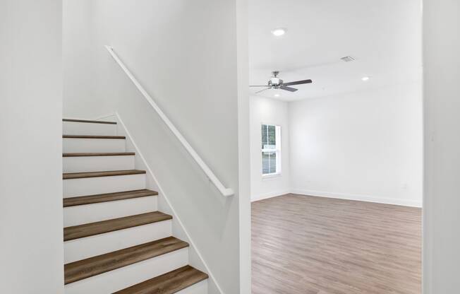 a living room with stairs and a ceiling fan