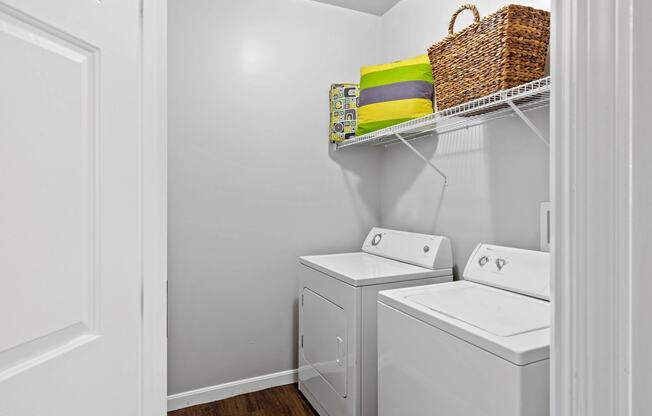 a laundry room with a washer and dryer and a basket on a shelf