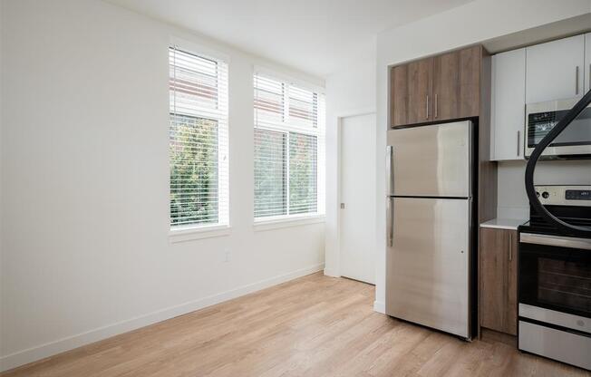 an empty kitchen with a stainless steel refrigerator and a window