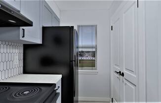 a kitchen with white cabinets and a black refrigerator