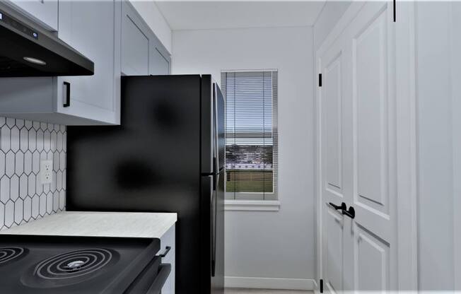 a kitchen with white cabinets and a black refrigerator