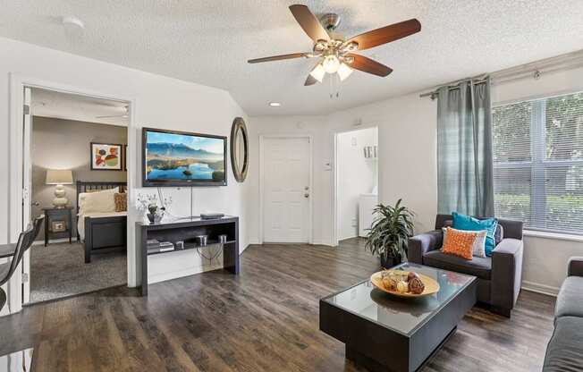 A modern living room with a dark wood floor and white walls.