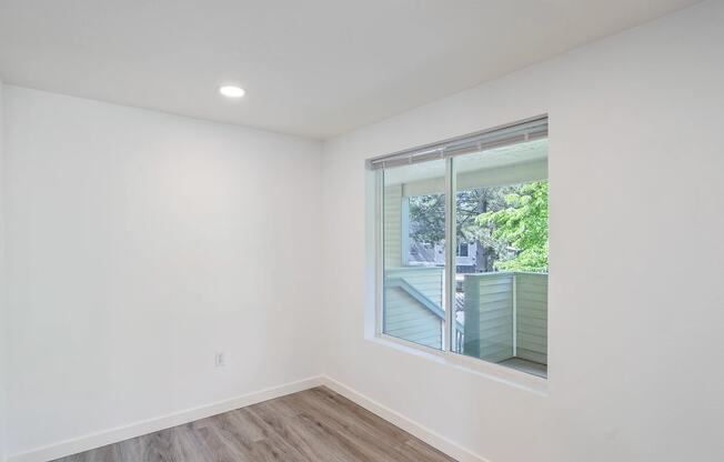 a bedroom with a large window and hardwood floors