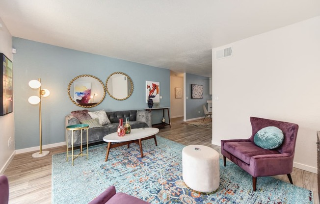 Living Room with Blue Pattern Rug, White Table, Gray Sofa, Purple Chair and Round Wall Mirrors