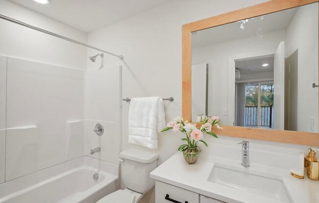 A white bathroom with a large mirror and a white toilet.