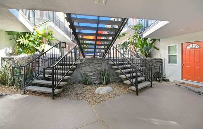 the stairway leading up to a building with a red door