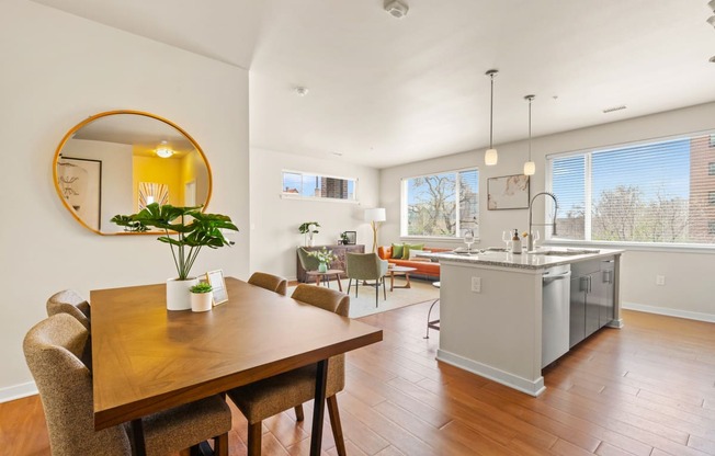 a modern dining room with a wooden table and chairs with a view into the stunning kitchen and luxurious living area at Sylvan Uptown, Denver, CO, 80203