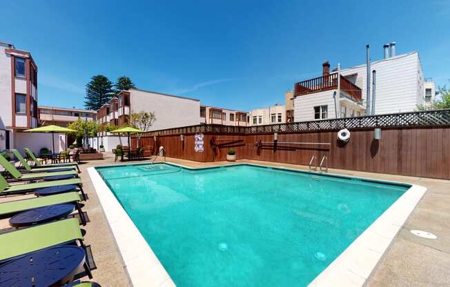 a swimming pool with chaise lounge chairs and umbrellas in front of a building