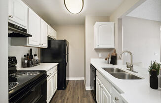 Model kitchen with white cabinets and black appliances at Vue at Baymeadows Apartments in Jacksonville, Florida