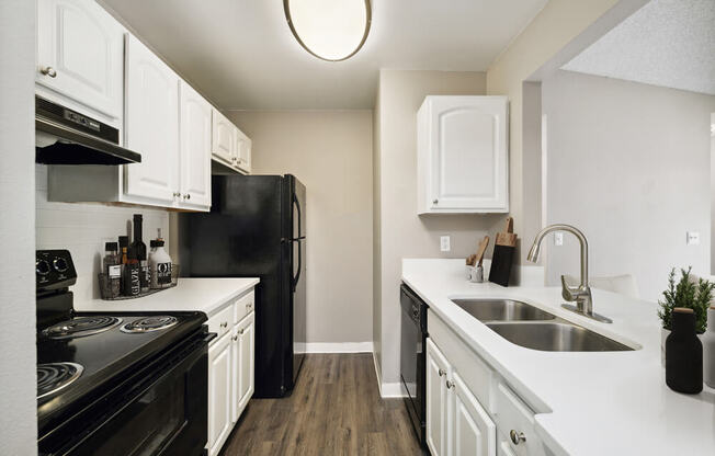 Model kitchen with white cabinets and black appliances at Vue at Baymeadows Apartments in Jacksonville, Florida