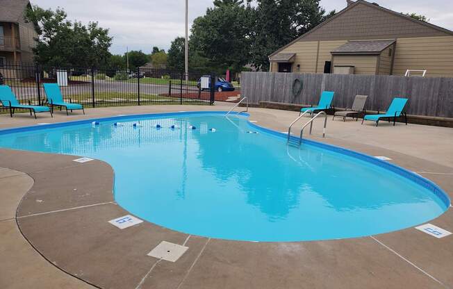 Willow Creek Apartments - Pool area with lounge chairs and clear water.