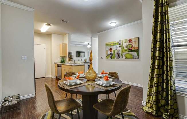 A dining room with a table set for two and a painting on the wall.