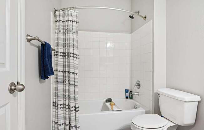 A white bathroom with a white toilet, white tub, and a white shower curtain.