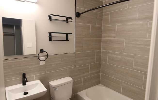 Modern bathroom featuring elegant tiled walls, sleek fixtures, and a cozy bathtub, perfect for relaxation.