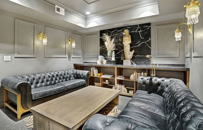 A black leather couch sits in a well-lit room with a wooden coffee table in front of it.