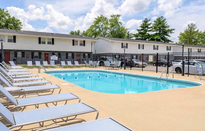 A pool surrounded by sun loungers and a building in the background at Spring Creek Townhomes Apartments, Illinois
