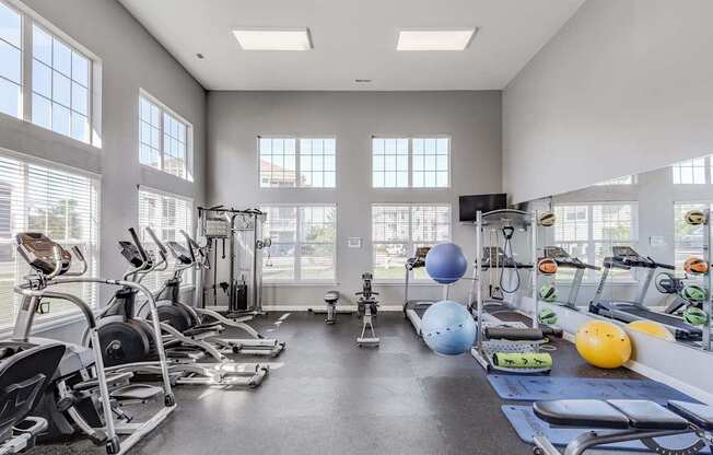 A gym with a variety of exercise equipment and a large window.