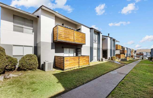 a row of townhomes with a sidewalk and grass