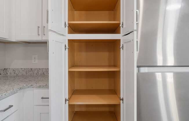 a kitchen with white cabinets and stainless steel appliances and an open refrigerator