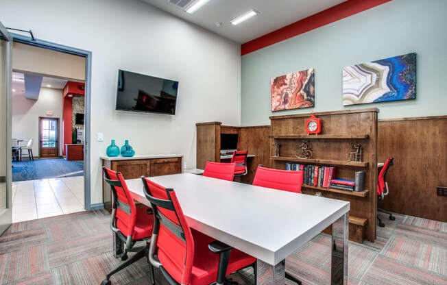 a conference room with a white table and red chairs