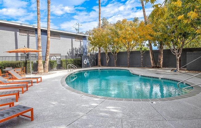 a swimming pool with benches and trees next to a building