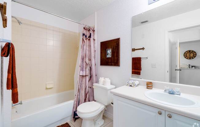A white bathroom with a toilet, sink, and shower.