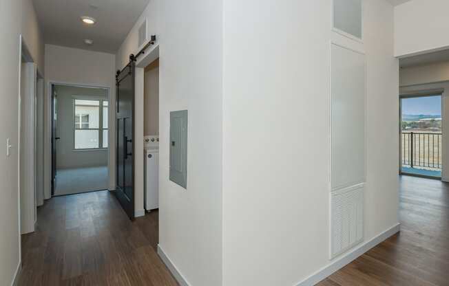 a hallway with white walls and wood flooring and a door to a balcony at The Crossings at Windsong, Prescott Valley, AZ