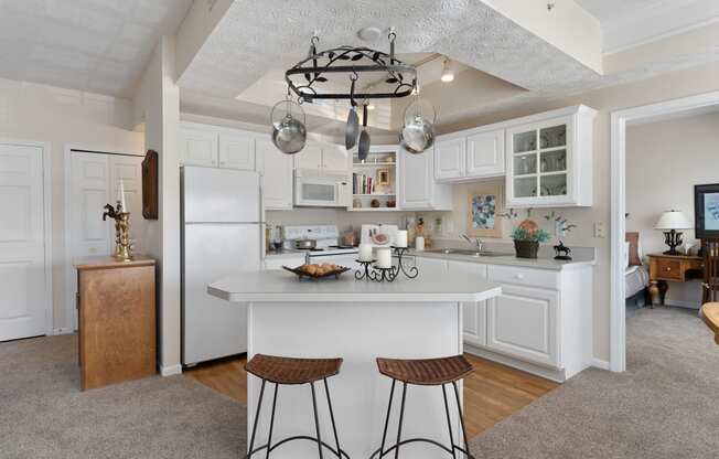 a kitchen with white cabinets and a white island with two stools