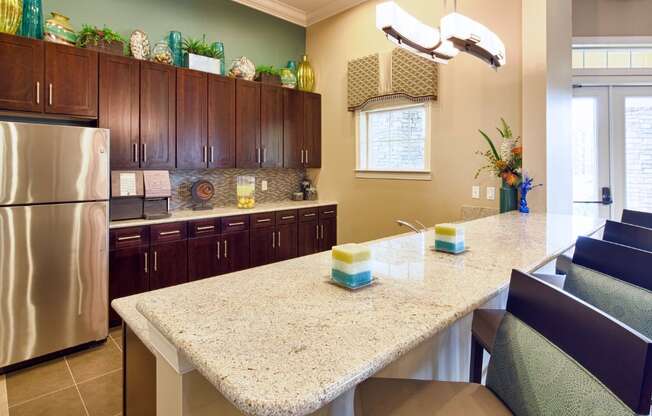 A kitchen with a granite counter top and a stainless steel refrigerator.