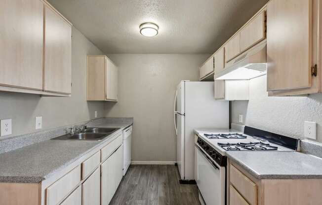 A kitchen with a white refrigerator, stove, and sink.