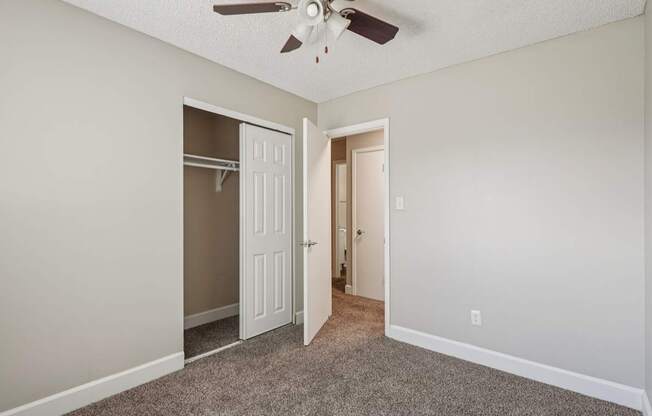 A room with a ceiling fan and two doors.
