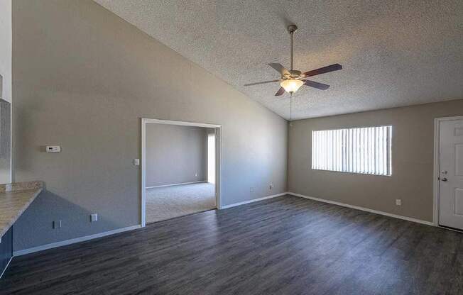 A room with a ceiling fan and a window with blinds.