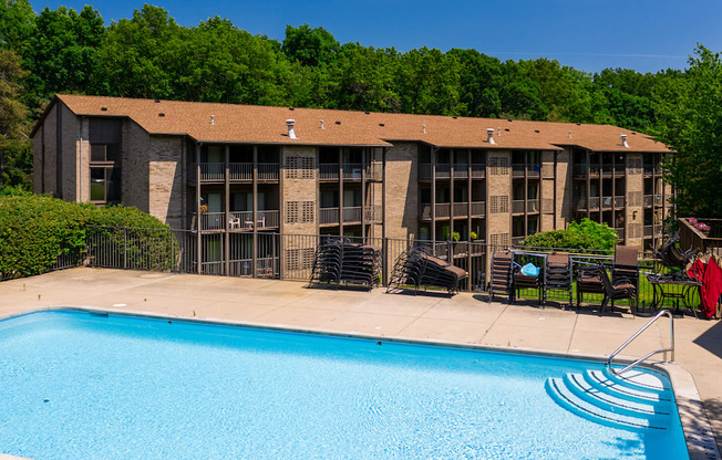 A swimming pool in front of a building with a person in a red shirt standing near the pool.