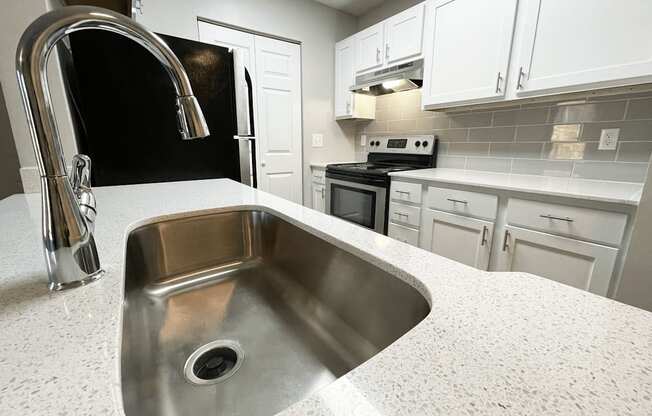 a kitchen with white cabinets and a stainless steel sink