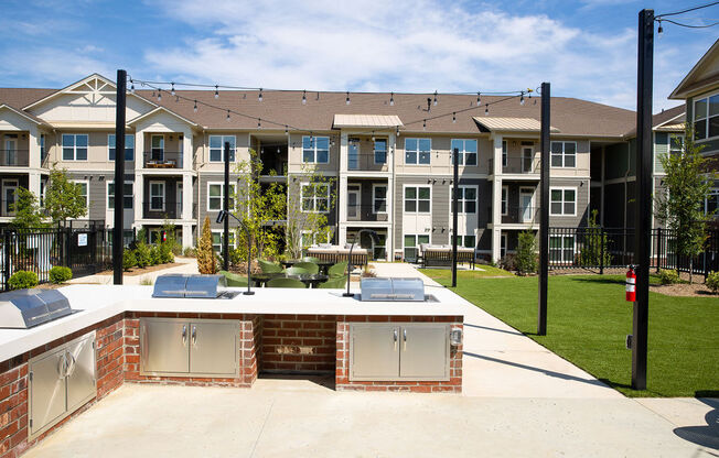 an outdoor entertaining area with a patio and lawn in front of an apartment building