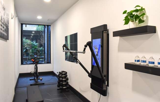 a gym with a treadmill and a tv in a room with a window  at Oslo, Seattle, Washington