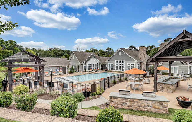 an outdoor pool with tables and umbrellas at the enclave at woodbury apartments