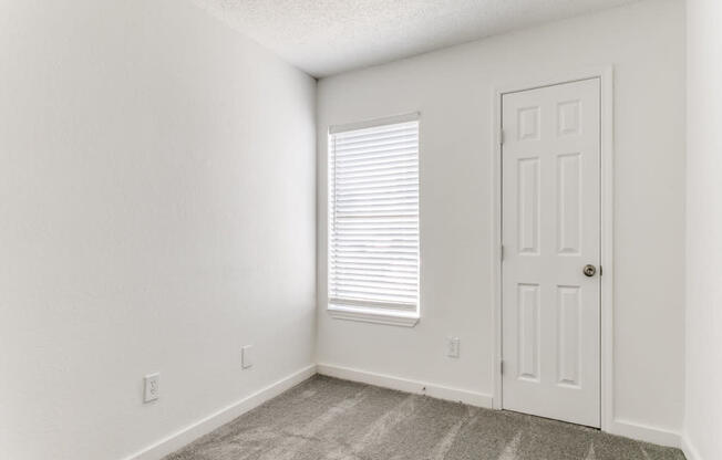 an empty room with a door and a window